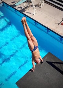 A diver doing a handstand off of a platform